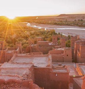 From above old town with stone constructions near narrow river between desert and beautiful heaven with clouds in Marrakesh, Morocco